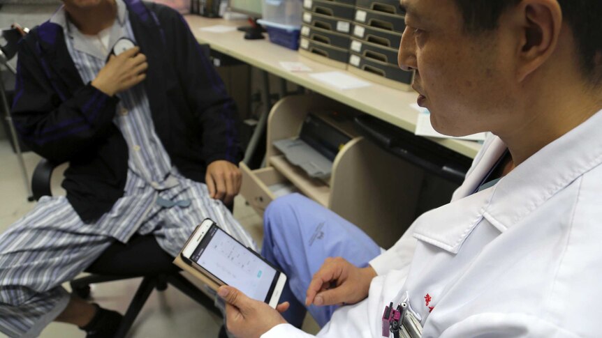A doctor in China uses a tablet to adjust the settings of a device implanted in a patient's brain.