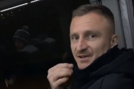 Besart Berisha sits on a bus and holds his pinched fingers close to his face