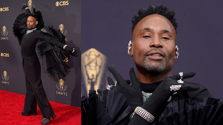 Billy Porter poses in a black jumpsuit with wings on his shoulders