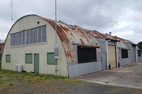 A large, curved-roof corrugated iron shed with rust covering the roof.