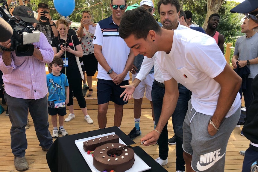 Thanasi Kokkinakis cuts a cake.