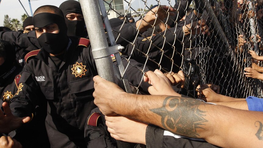 Relatives of inmates at Apodaca prison in Mexico attempt to breach the security fence.