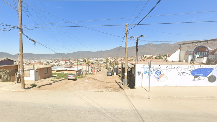 A streetscape in Baja California, with power poles and a graffitied wall