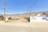 A streetscape in Baja California, with power poles and a graffitied wall