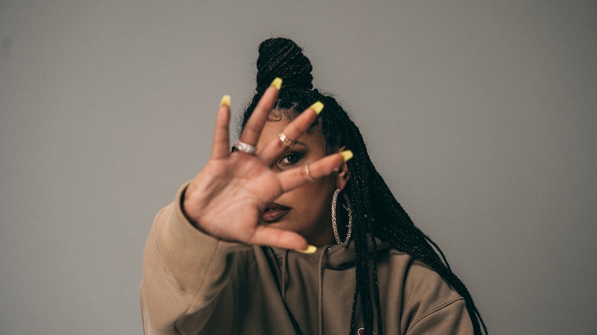 Rapper BARKAA holds her hand up to the camera