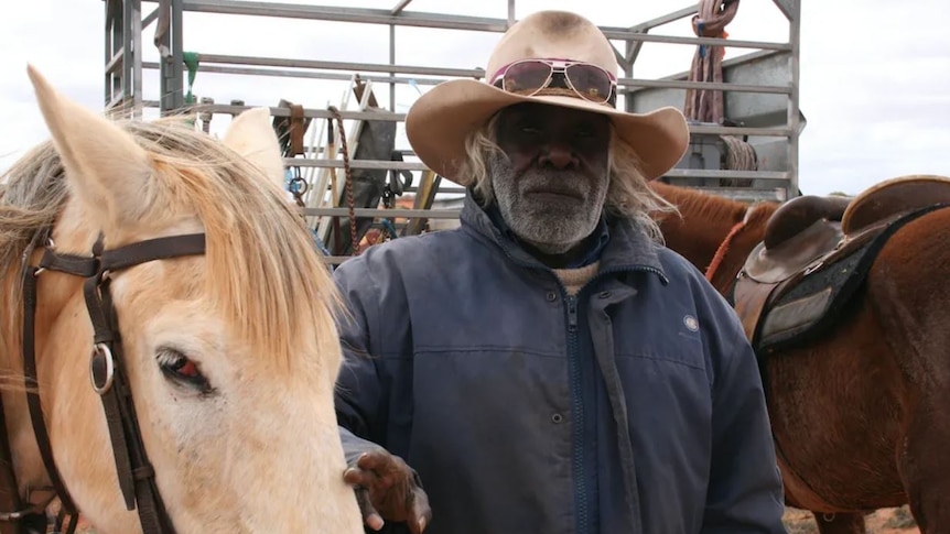 An Aboriginal Stockman standing next to his horses