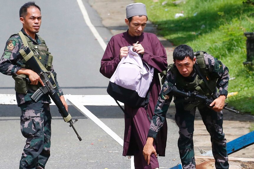 Government troops frisk a Muslim man at a checkpoint leading to Marawi city.