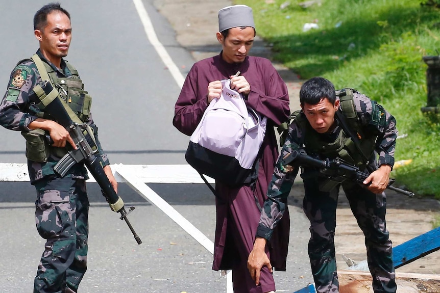 Government troops frisk a Muslim man at a checkpoint leading to Marawi city.