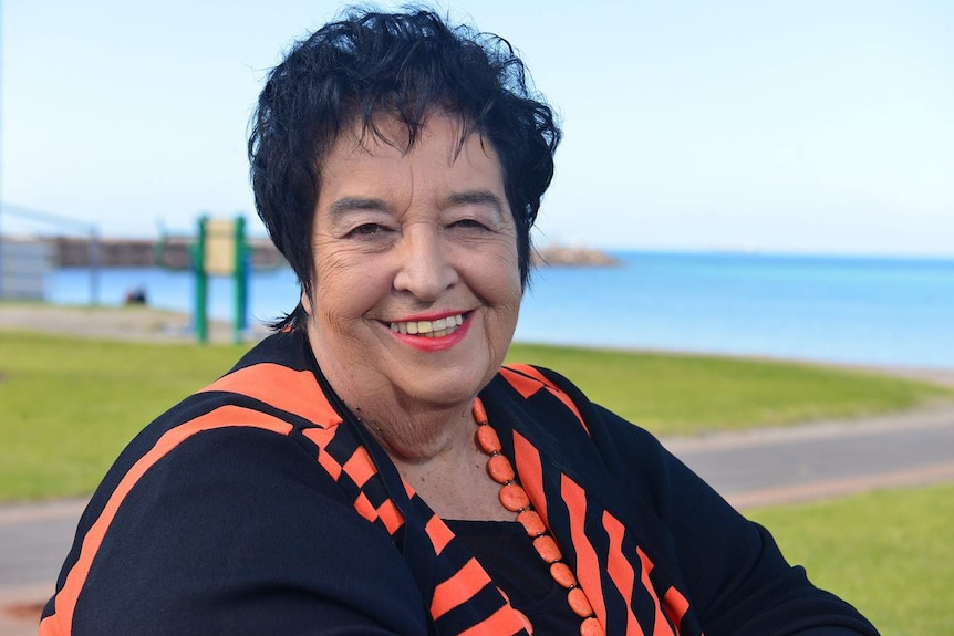 Woman sitting in front of the coastline of town