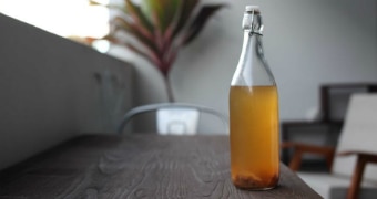 A bottle of kombucha on a table.