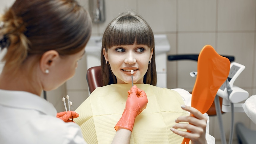 A woman in a dentist chair choosing how white to make her new teeth.