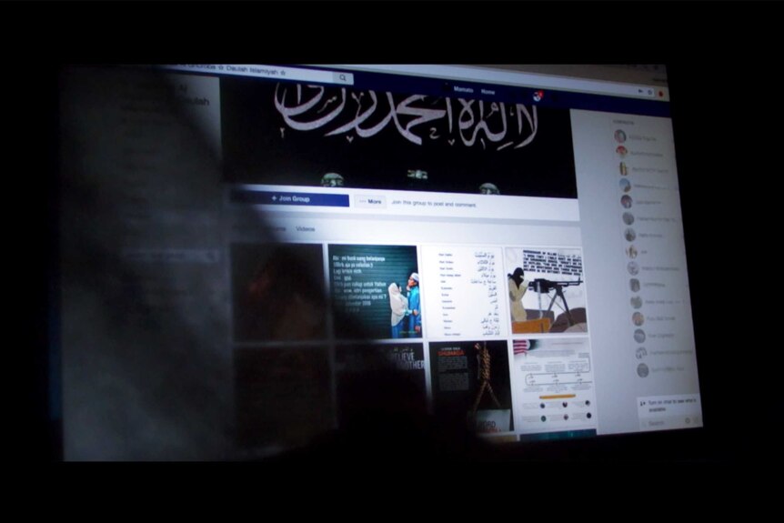 A facebook page with Arabic characters on a computer screen is partially obscured by a black cloth.