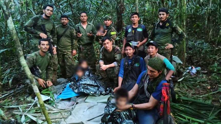 Colombian military pose with children for a group found in jungle, with the childrens' faces blurred