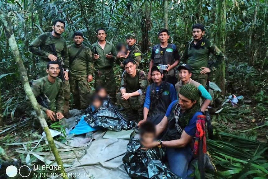 Colombian military pose with children for a group found in jungle, with the childrens' faces blurred