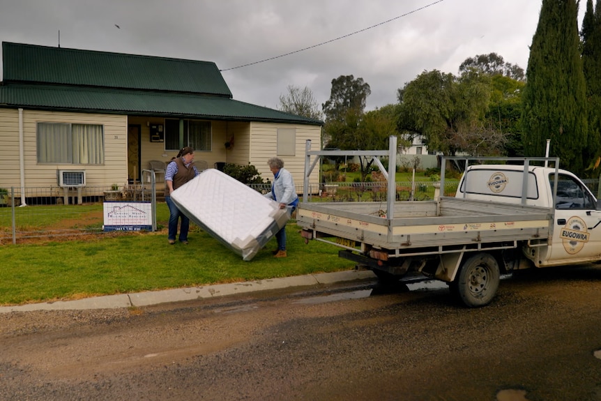 Eugowra resident Kim Storey and Back Roads' Heather Ewart moving mattresses off a truck and into someone's house. 