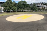 A helipad with a big H painted on it in a park.