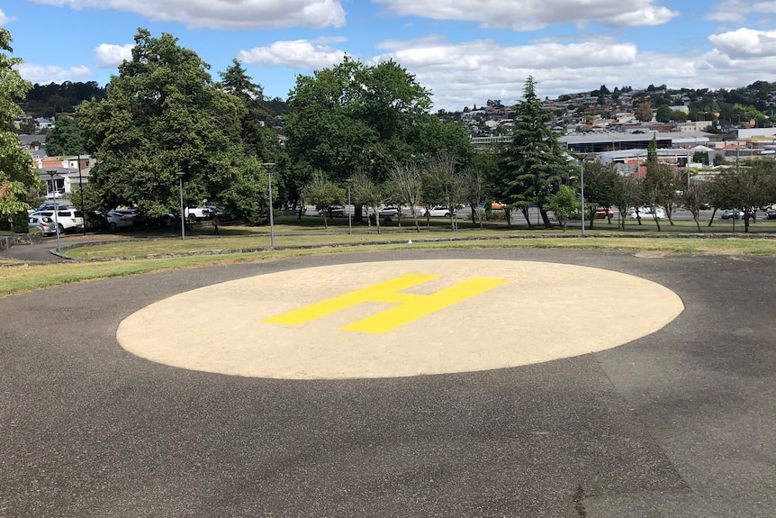 A helipad with a big H painted on it in a park.