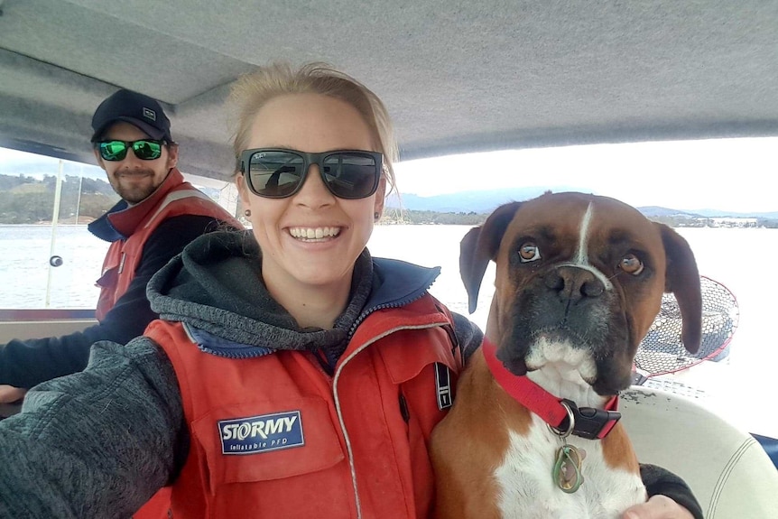 Naomi Wisby and husband Brody Corbett on a boat with a dog.