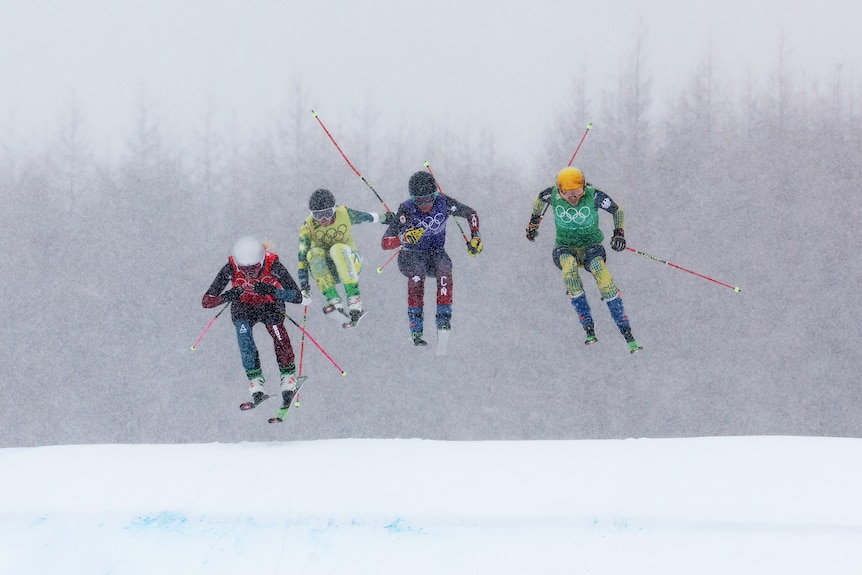 Four skiers clear a snowbank 