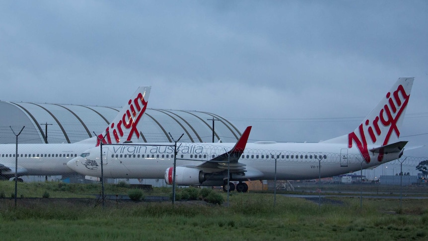 Two Virgin planes in front of a hangar