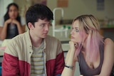 A teenage boy and girl stare into each other's eyes.