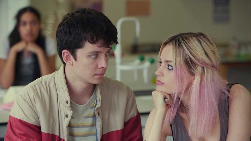 A teenage boy and girl stare into each other's eyes.