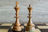 A king and a queen pieces sit on a chess board.