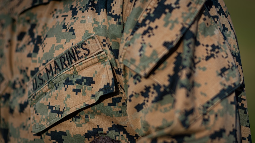 A close-up of someone wearing a camouflage US Marines uniform.