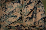 A close-up of someone wearing a camouflage US Marines uniform.