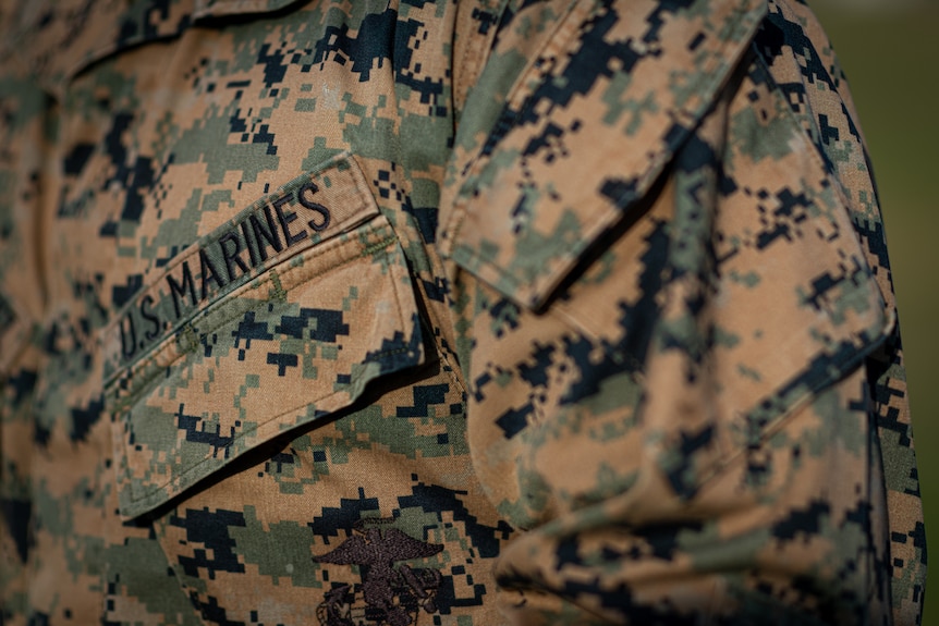 A close-up of someone wearing a camouflage US Marines uniform.