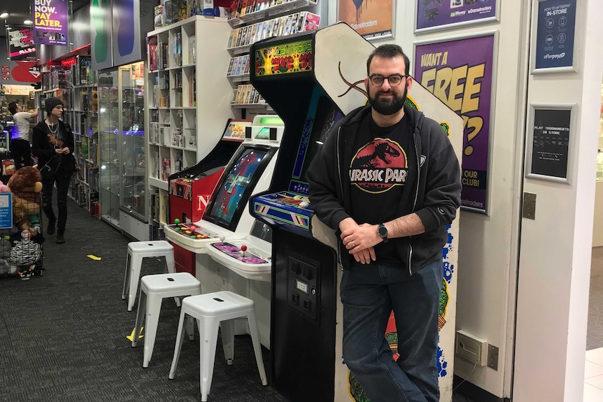 Benn Banasik standing in front of part of his arcade machine collection in his games store in southwest Sydney.