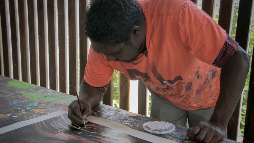 Indigenous artist Slias Hobson painting a canvas.
