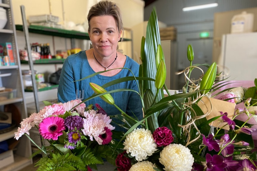 Wendy Day standing behind bunches of flowers.