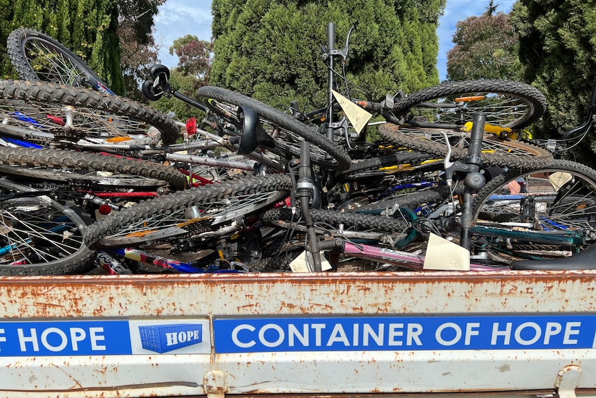 A heap of old bicycles in a big metal bin