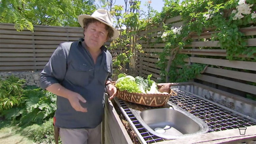 Man in hat in garden with metal mesh and sink placed over compost bay