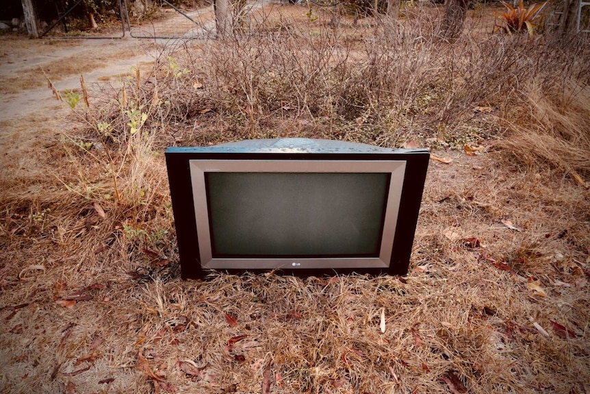 old television abandoned and left in dead grass outside