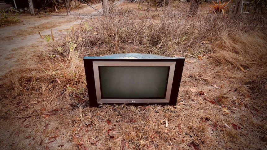 old television abandoned and left in dead grass outside