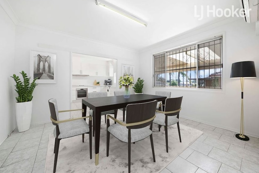 The walls and tiled floor are white inside a living space with a dining table.