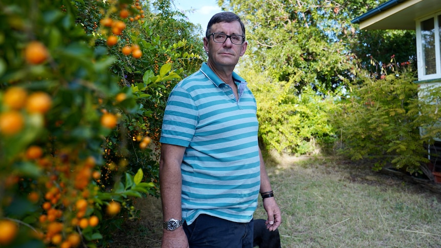 A middle-aged, bespectacled man standing in a garden.