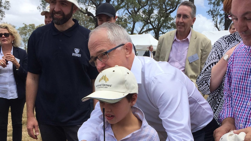 People take photos of the Prime Minister with a boy controlling a robot, Camden near Sydney