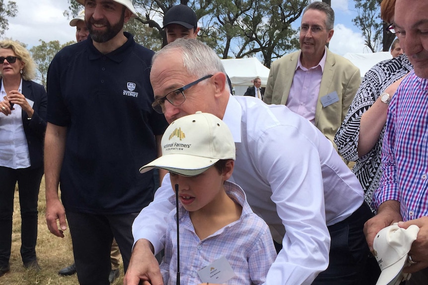 People take photos of the Prime Minister with a boy controlling a robot, Camden near Sydney