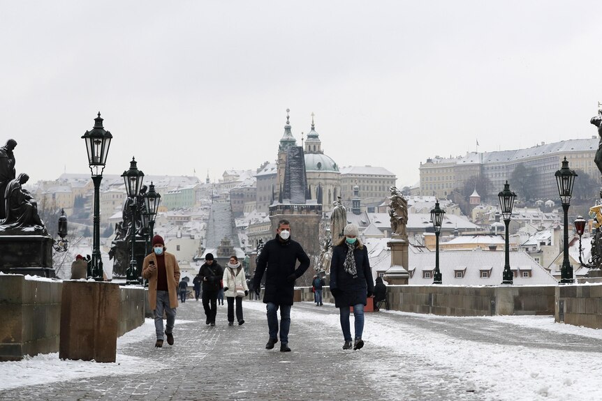 People cross the medieval Charles Bridge after snowfall in Prague