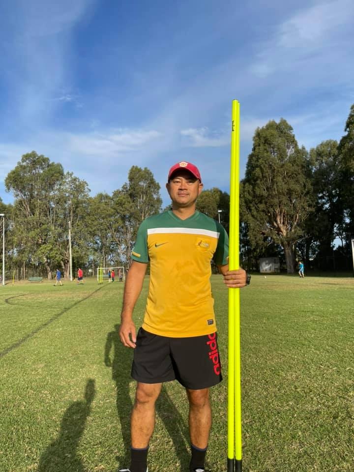 A soccer coach stands by the goalposts