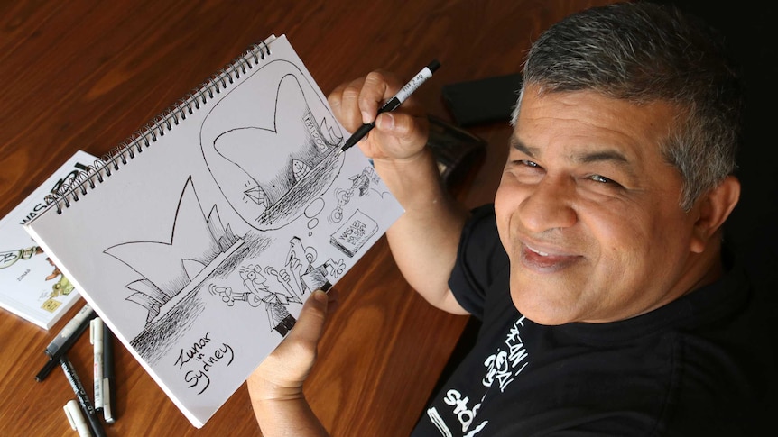 Zunar looks up from drawing a cartoon.