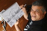 Zunar looks up from drawing a cartoon.