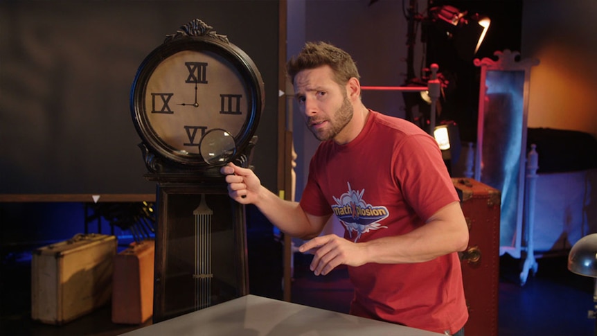 Man holds magnifying glass up to clock with Roman numerals