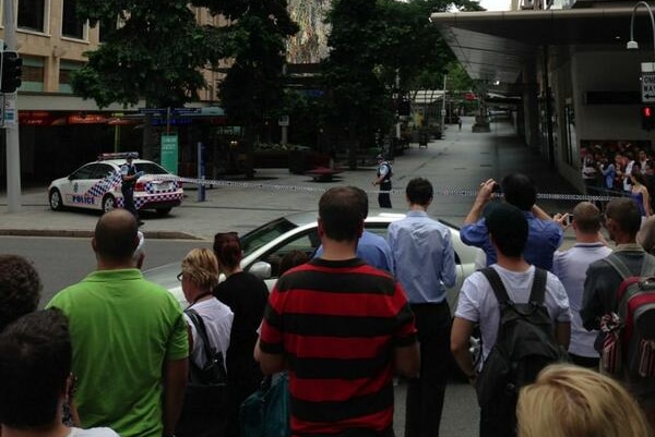 People in Brisbane city stand at one end of the Queen Street Mall amid an emergency incident.
