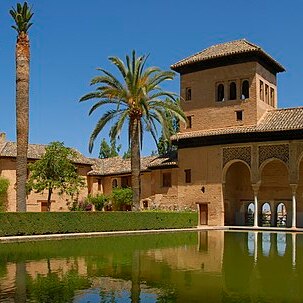 A still pool reflecting a Spanish palace.