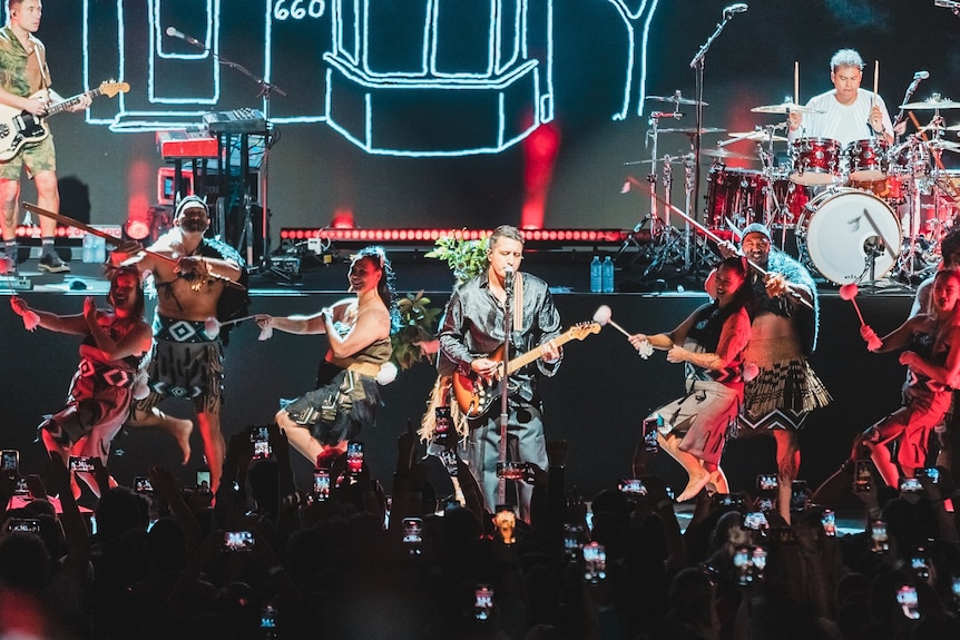 Maori dancers and First Nations dancers perform on a stage with kiwi bands SIX60 in traditional dress