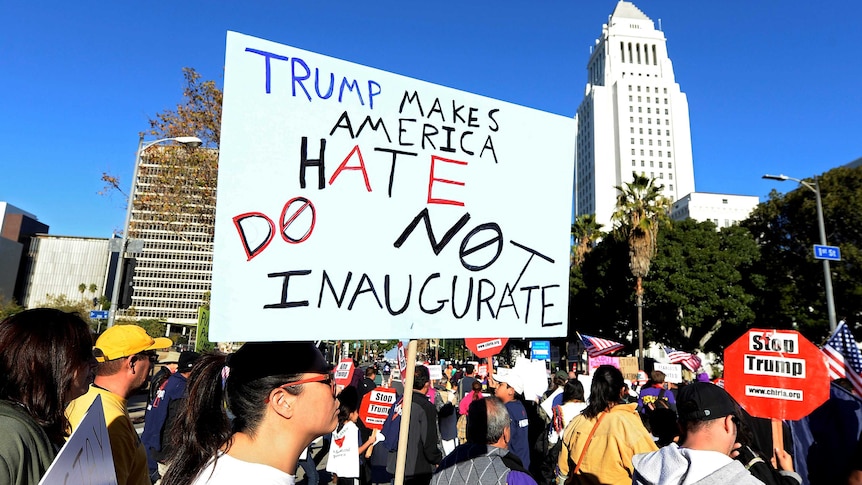 Protesters hold up signs during a march and rally against the United States President-elect Donald Trump.